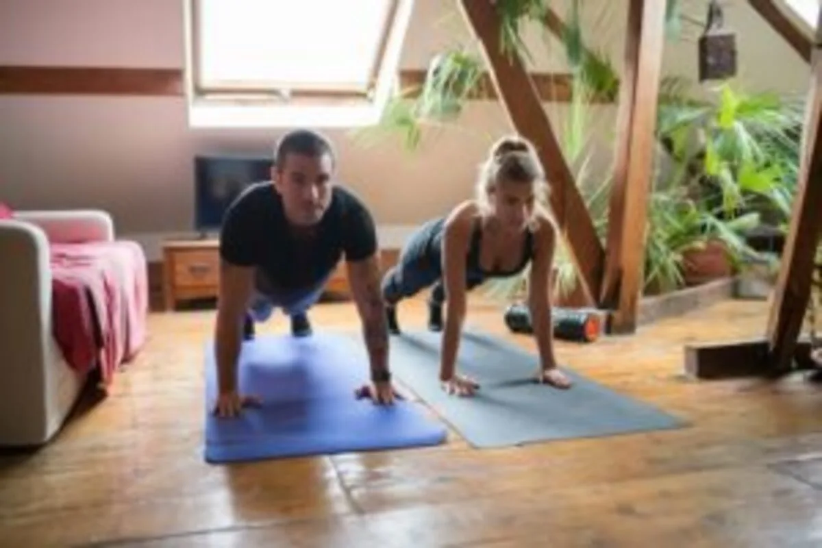 Casal fazendo flexões em colchonetes em casa, exercitando-se juntos