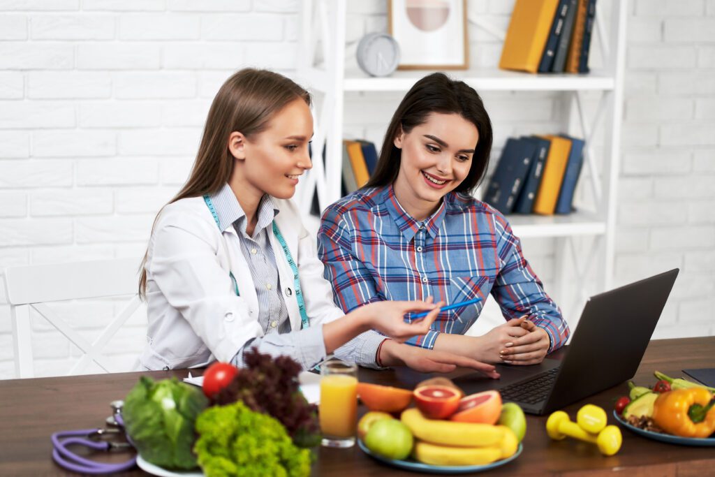 Uma nutricionista sorridente aconselha uma jovem paciente sobre alimentação
